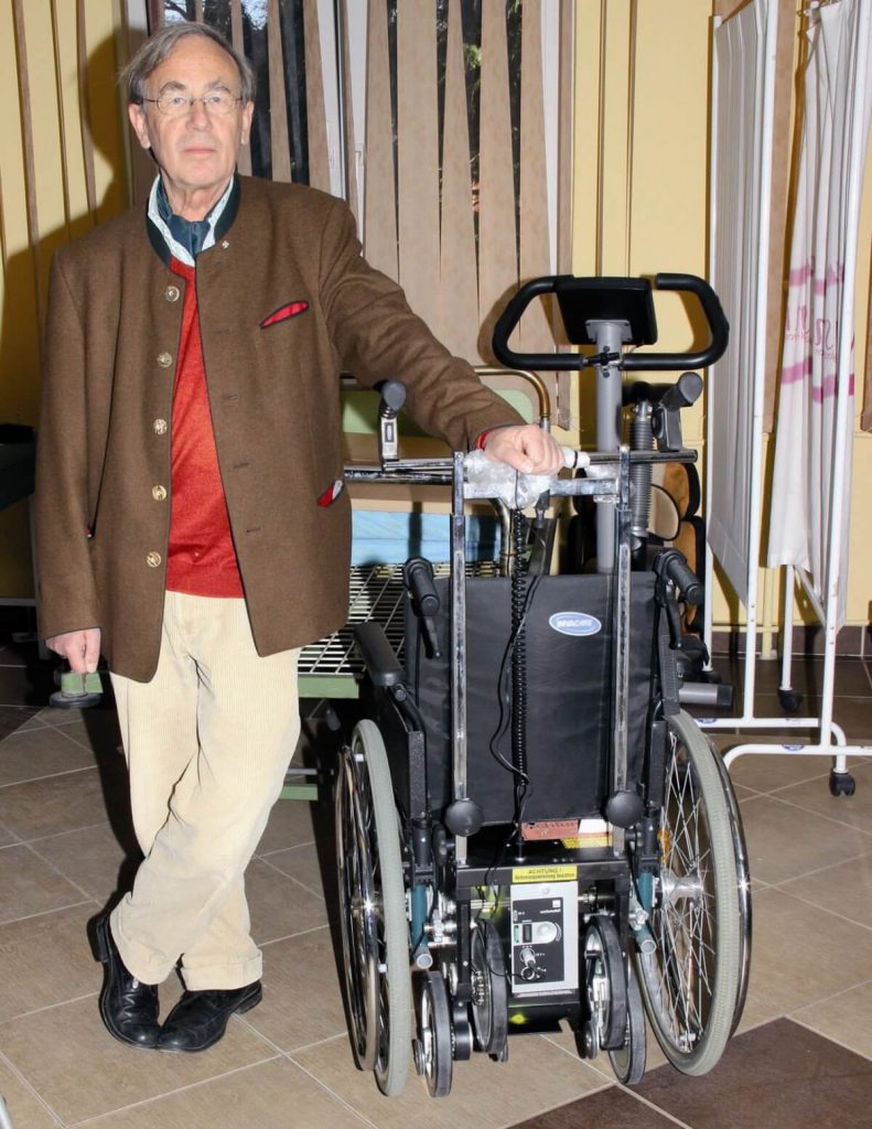 Dr Chrystian Meyl obok elektrycznego wózka inwalidzkiego
