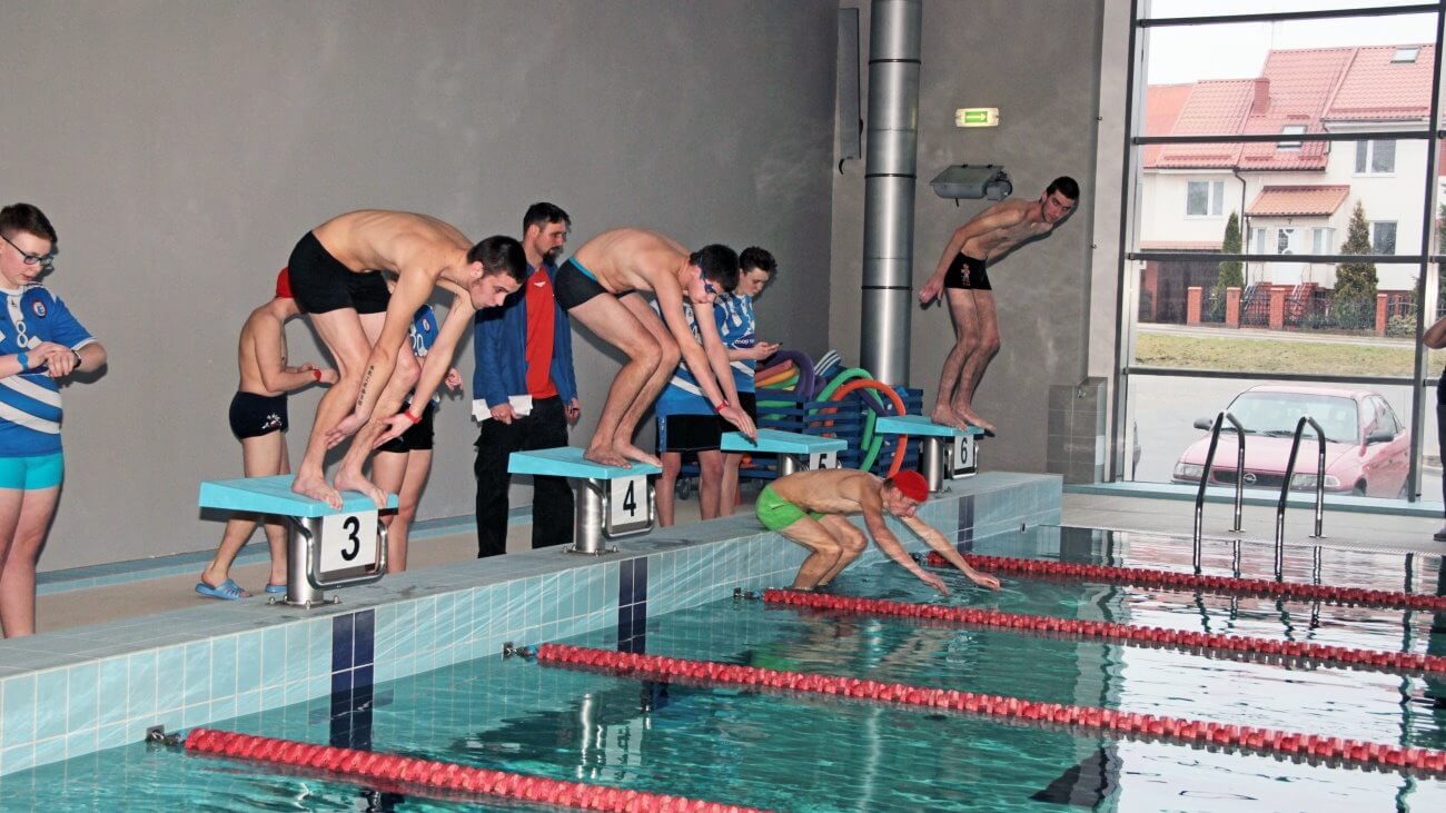 Uczestnicy zawodów pływackich skaczą do wody