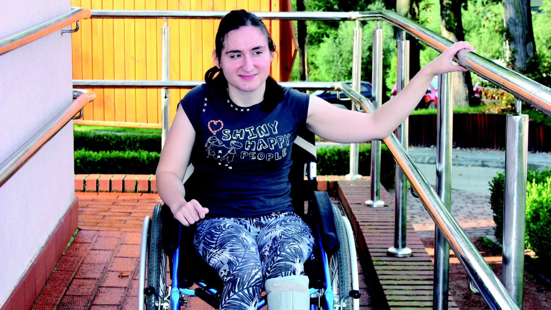 Uczestniczka Warsztatu Terapii Zajęciowej zjeżdża z rampy na wózku inwalidzkim