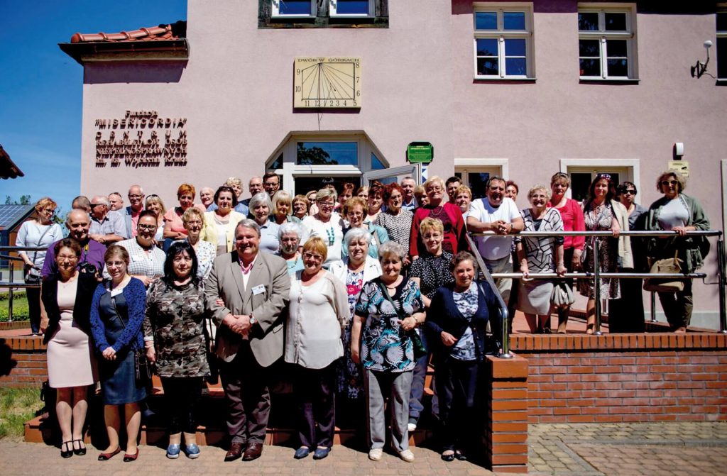 Zdjęcie grupowe gości przed budynkiem Warsztatu Terapii Zajęciowego