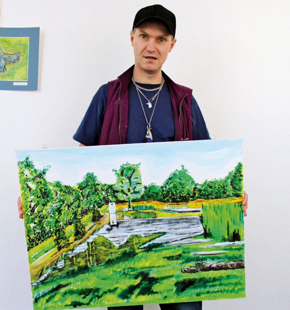 Waldemar Paszke trzyma obraz przedstawiający jezioro