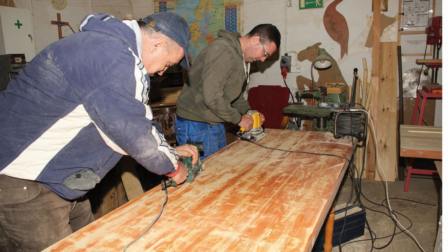 Uczestnicy Warsztatu Terapii Zajęciowej w Kwidzynie szlifują stół w pracowni edukacyjno-stolarskiej