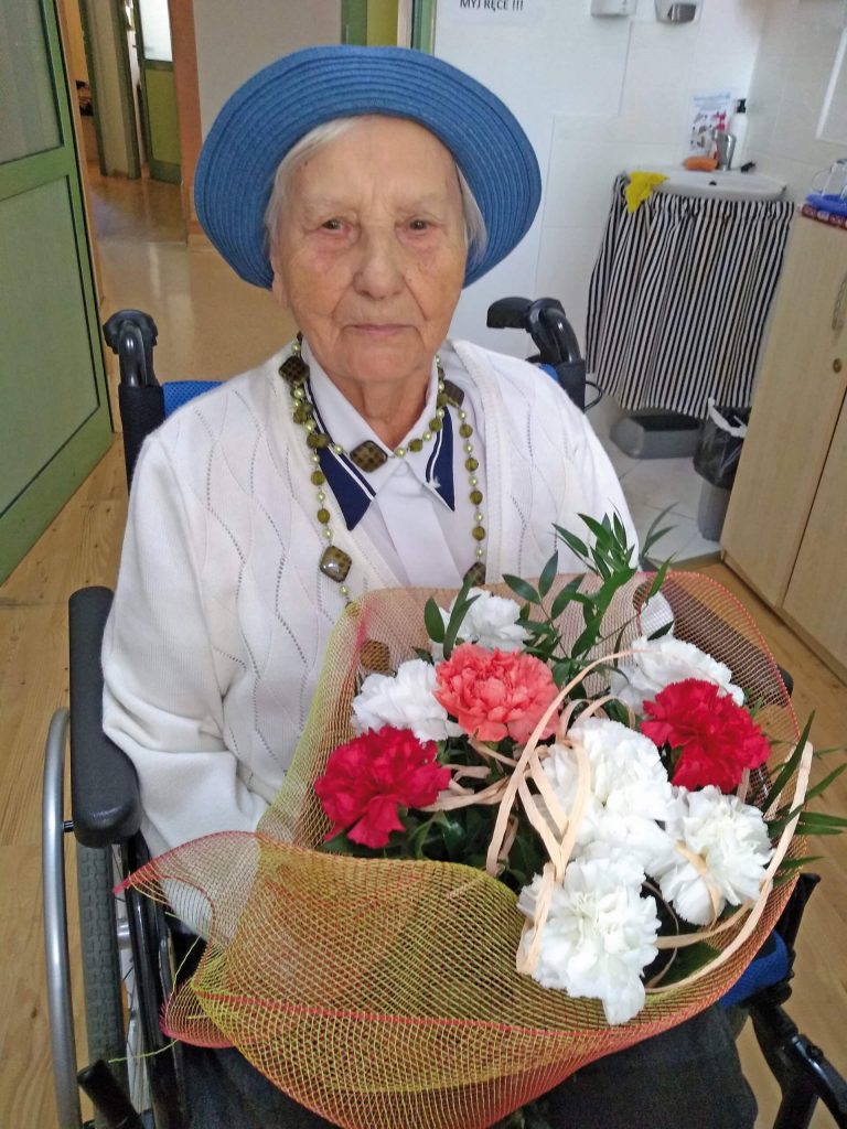 Seniorka z bukietem białych i czerwonych kwiatów