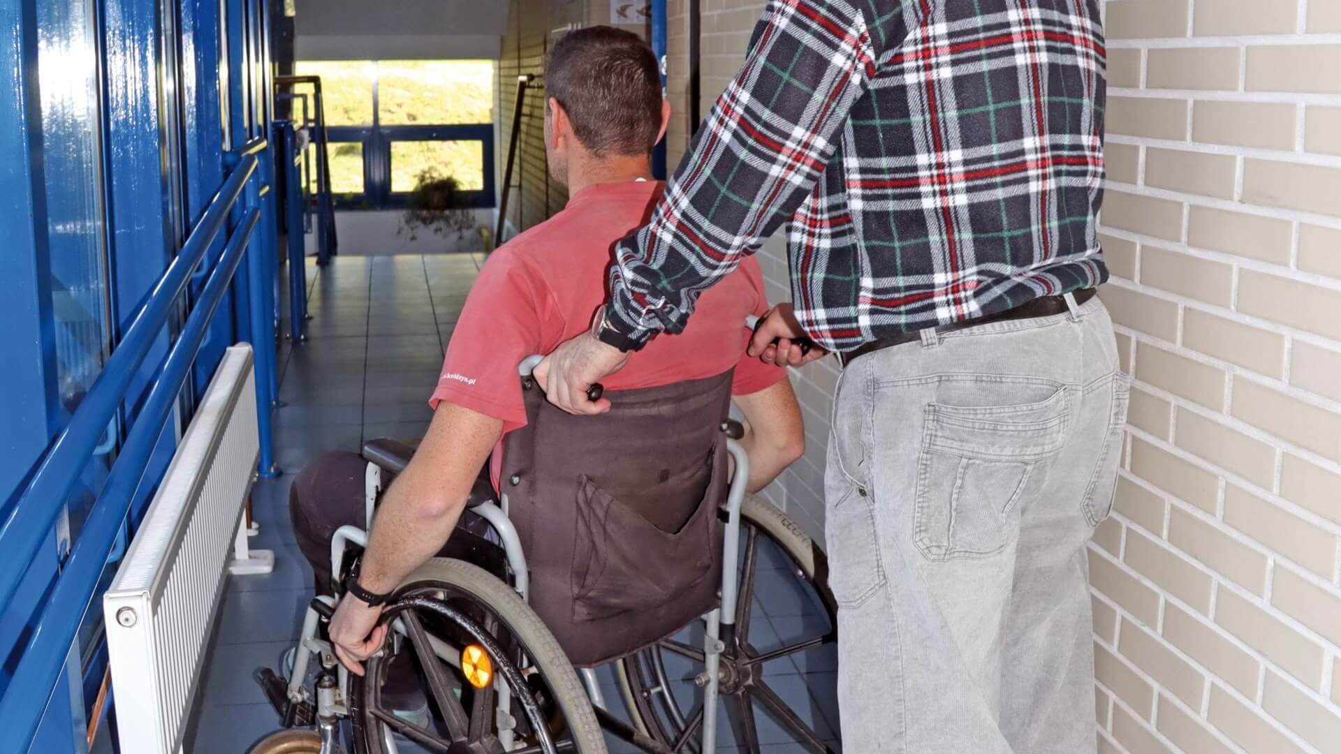 Osoba niepełnosprawna na wózku inwalidzkim z asystentem