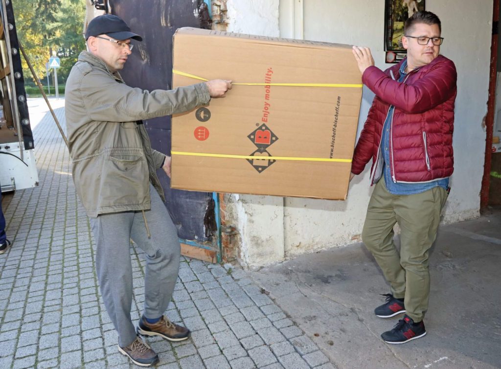 Uczestnik i instruktor Warsztatu Terapii Zajęciowej w Kwidzynie przenoszą zapakowany dar