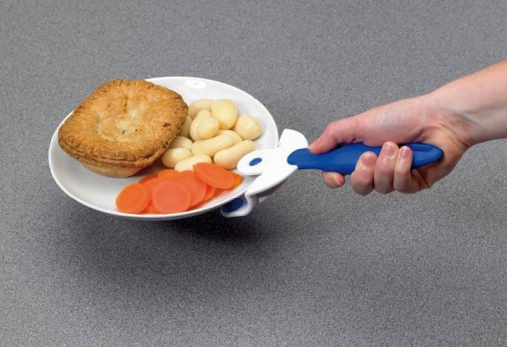 Dłoń trzymająca talerz z jedzeniem przy użyciu chwytaka do gorących talerzy