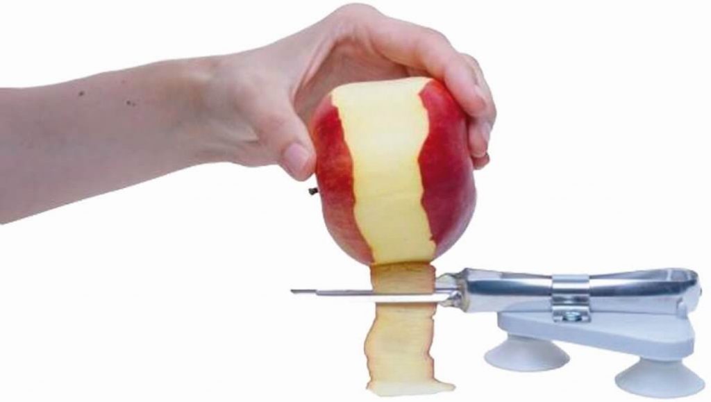 Dłoń trzymająca obierane jabłko nad obieraczką na przyssawki