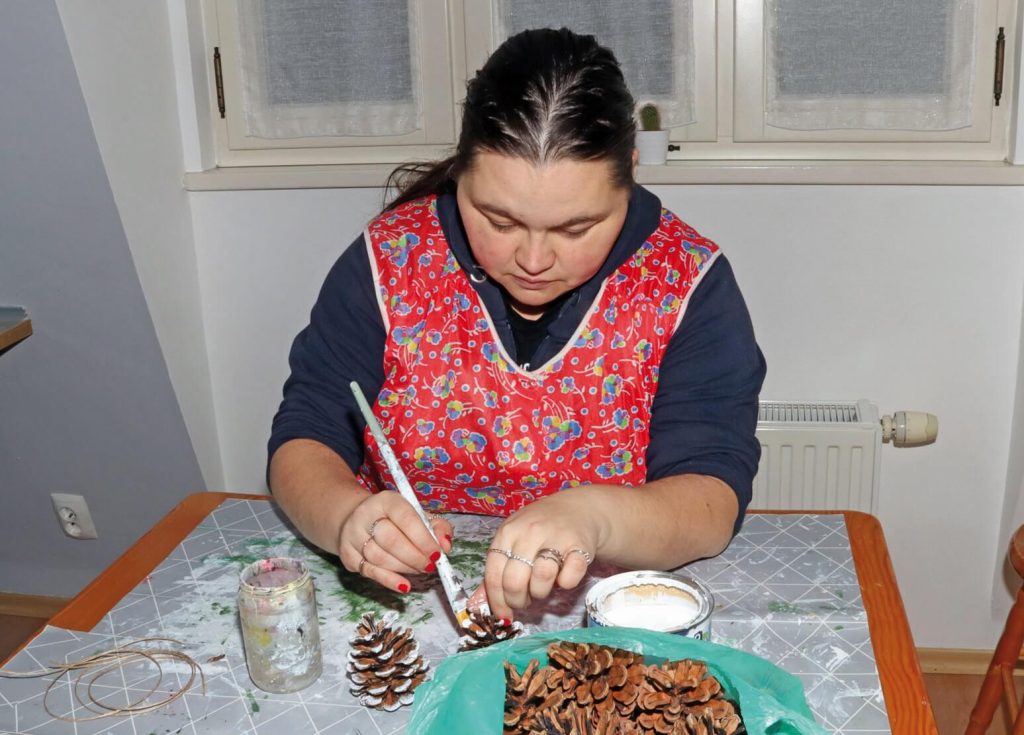 Uczestniczka Warsztatu Terapii Zajęciowej w Górkach maluje szyszki