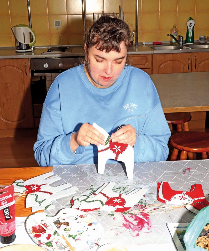 Uczestniczka Warsztatu Terapii Zajęciowej w Górkach przygotowuje świąteczne ozdoby w kształcie koni