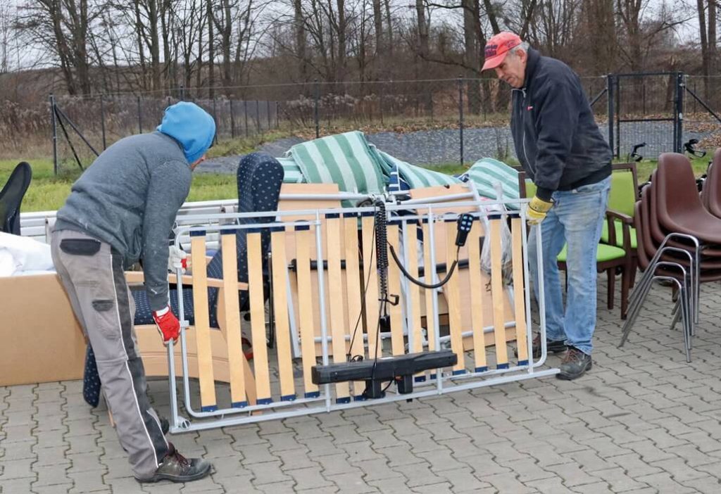 Uczestnicy Warsztatu Terapii Zajęciowej w Górkach przenoszą łóżko elektryczne