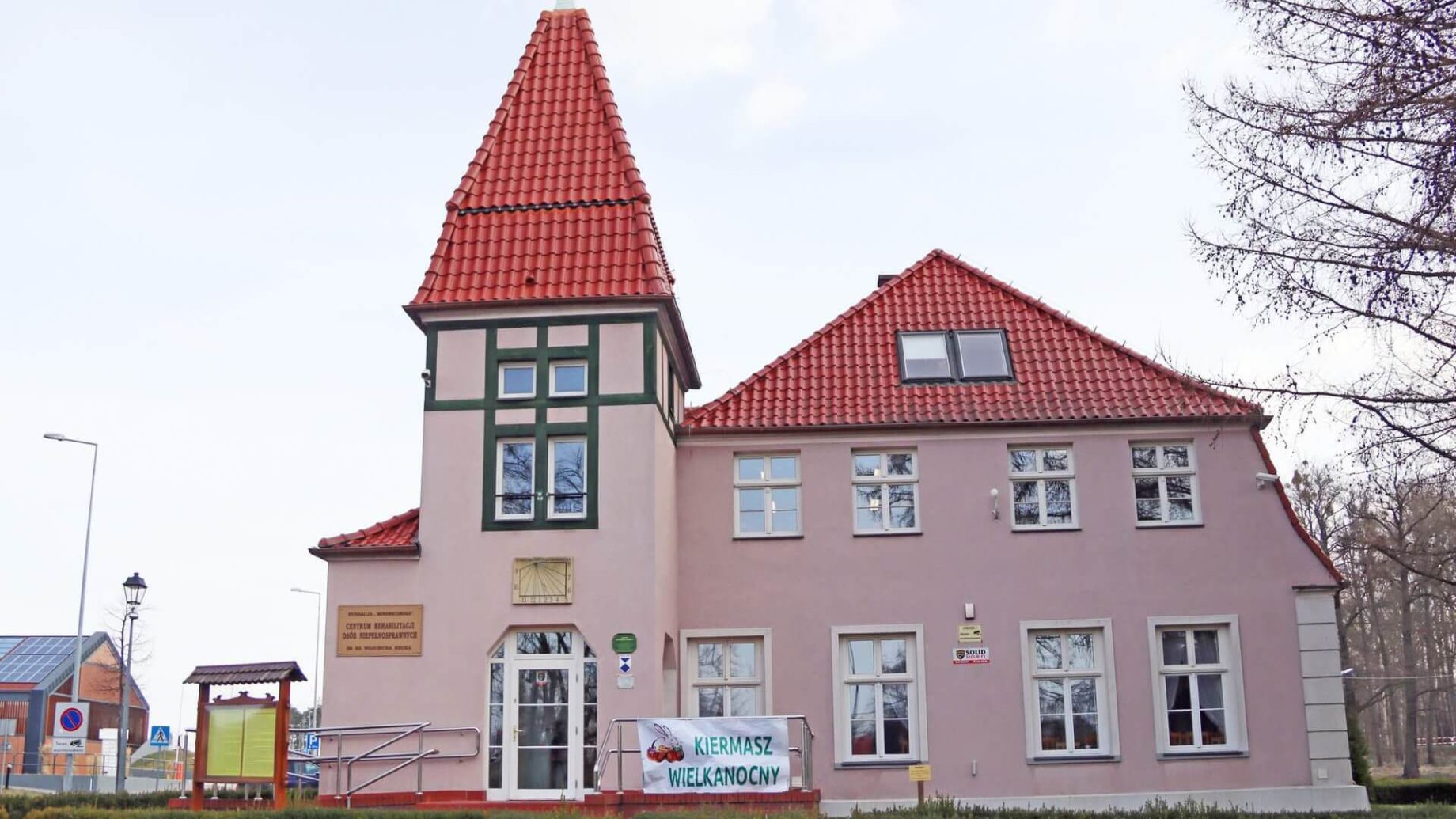 Siedziba Warsztatu Terapii Zajęciowej w Górkach. Na barierce baner z napisem „Kiermasz wielkanocny”