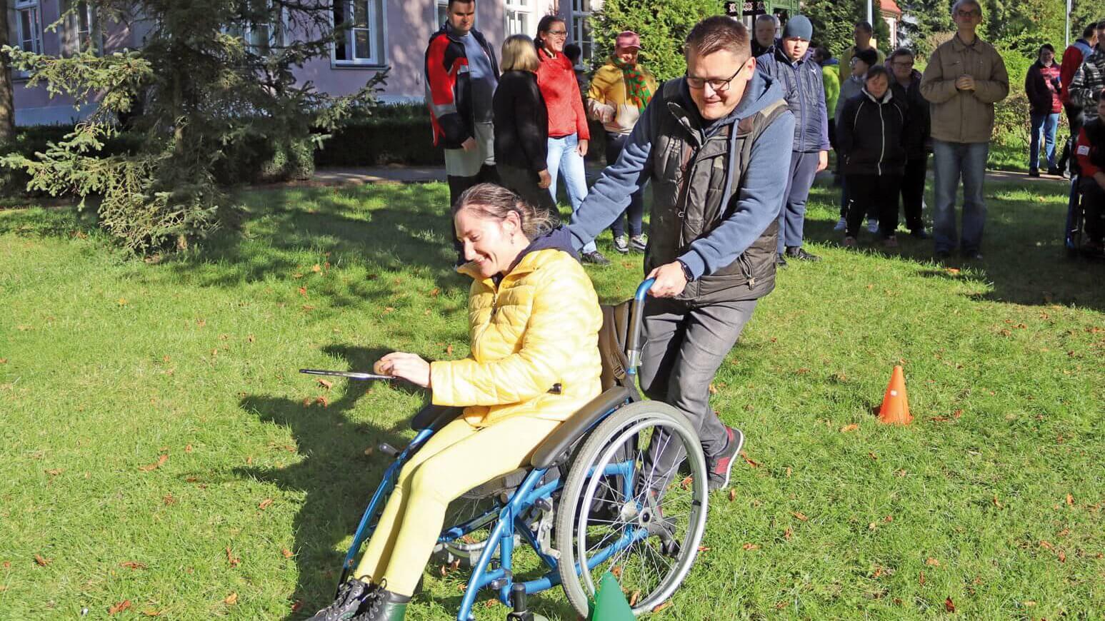 Uczestniczka Warsztatu Terapii Zajęciowej w Górkach na wózku prowadzona przez intruktora