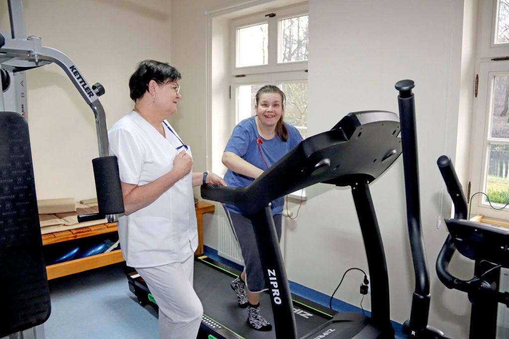 Uczestniczka Warsztatu Terapii Zajęciowej w Górkach na bieżni wraz z rehabilitantką