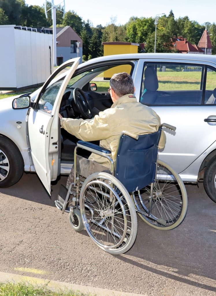 Osoba na wózku inwalidzkim wsiada do samochodu