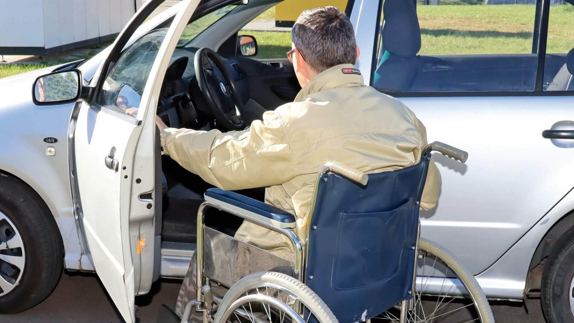 Osoba na wózku inwalidzkim wsiada do samochodu