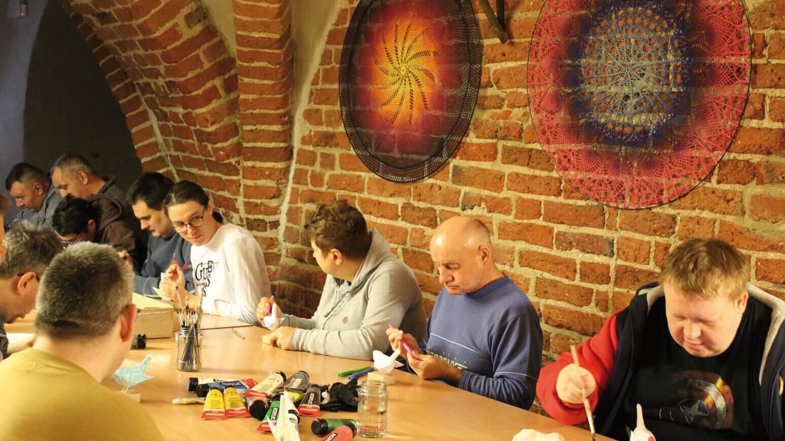 Uczestnicy Warsztatu Terapii Zajęciowej w Górkach malują i kolorują ptaki z papieru mâché podczas zajęć w kwidzyńskim zamku