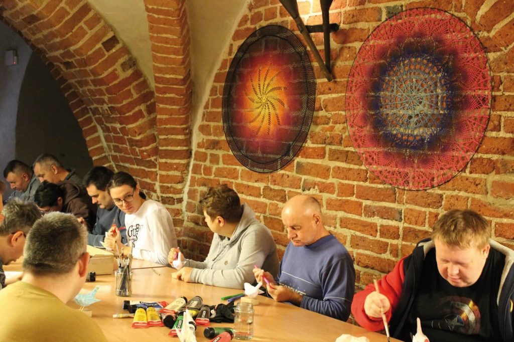 Uczestnicy Warsztatu Terapii Zajęciowej w Górkach malują i kolorują ptaki z papieru mâché podczas zajęć w kwidzyńskim zamku