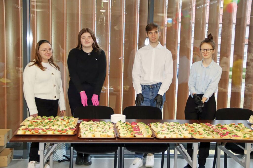 Uczennice i uczniowie Technikum Żywienia i Usług Gastronomicznych i Technikum Hotelarskiego z Zespołu Szkół nr 2 w Kwidzynie przy stołach z posiłkami