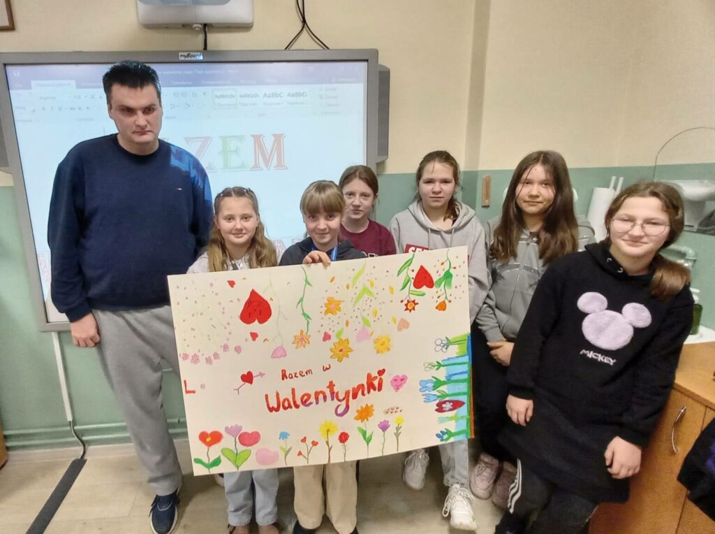 Uczestnik Warsztatu Terapii Zajęciowej w Górkach i dzieci z plakatem walentynkowym