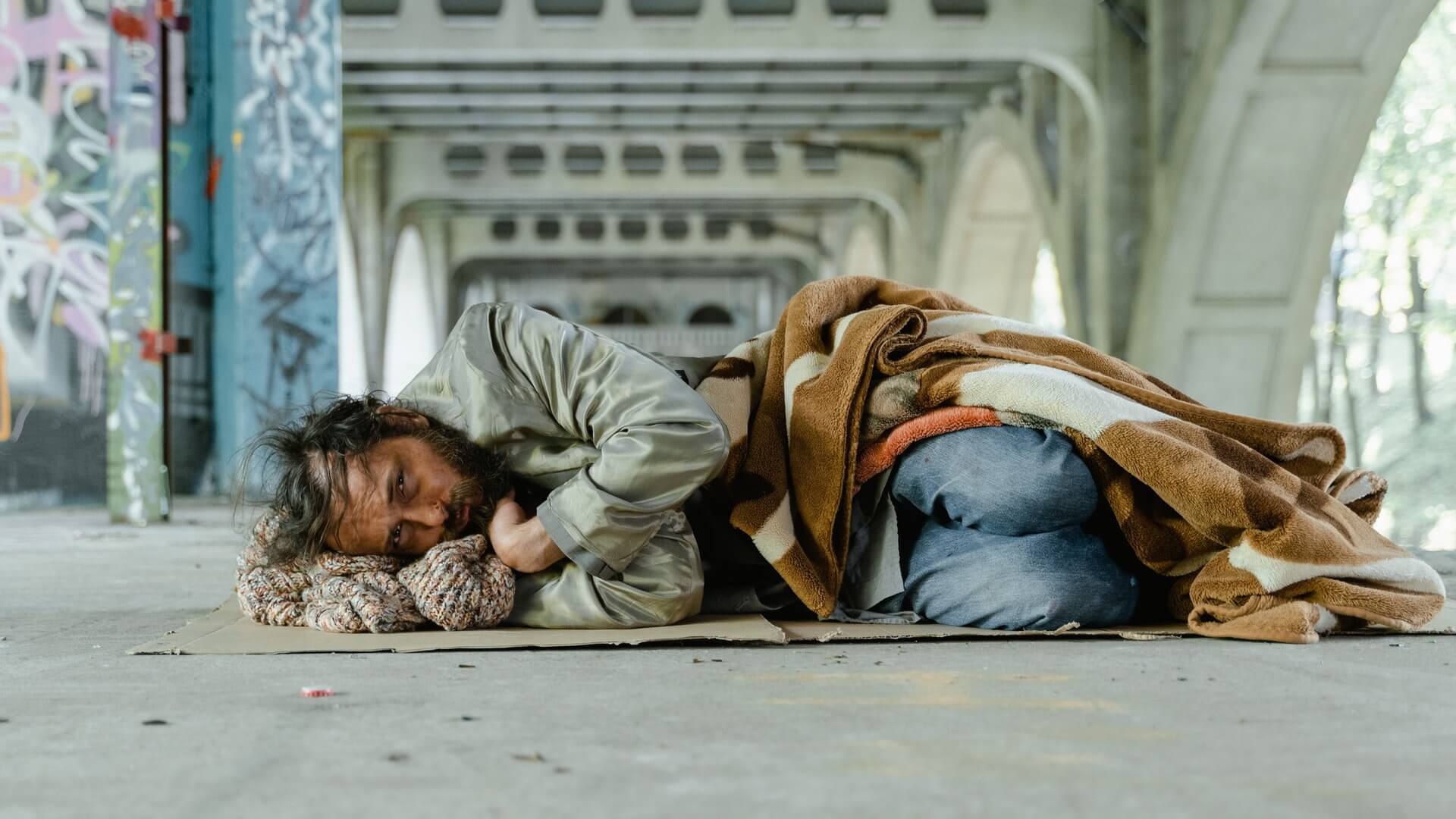 Bezdomny mężczyzna leżący na kawałku kartonu